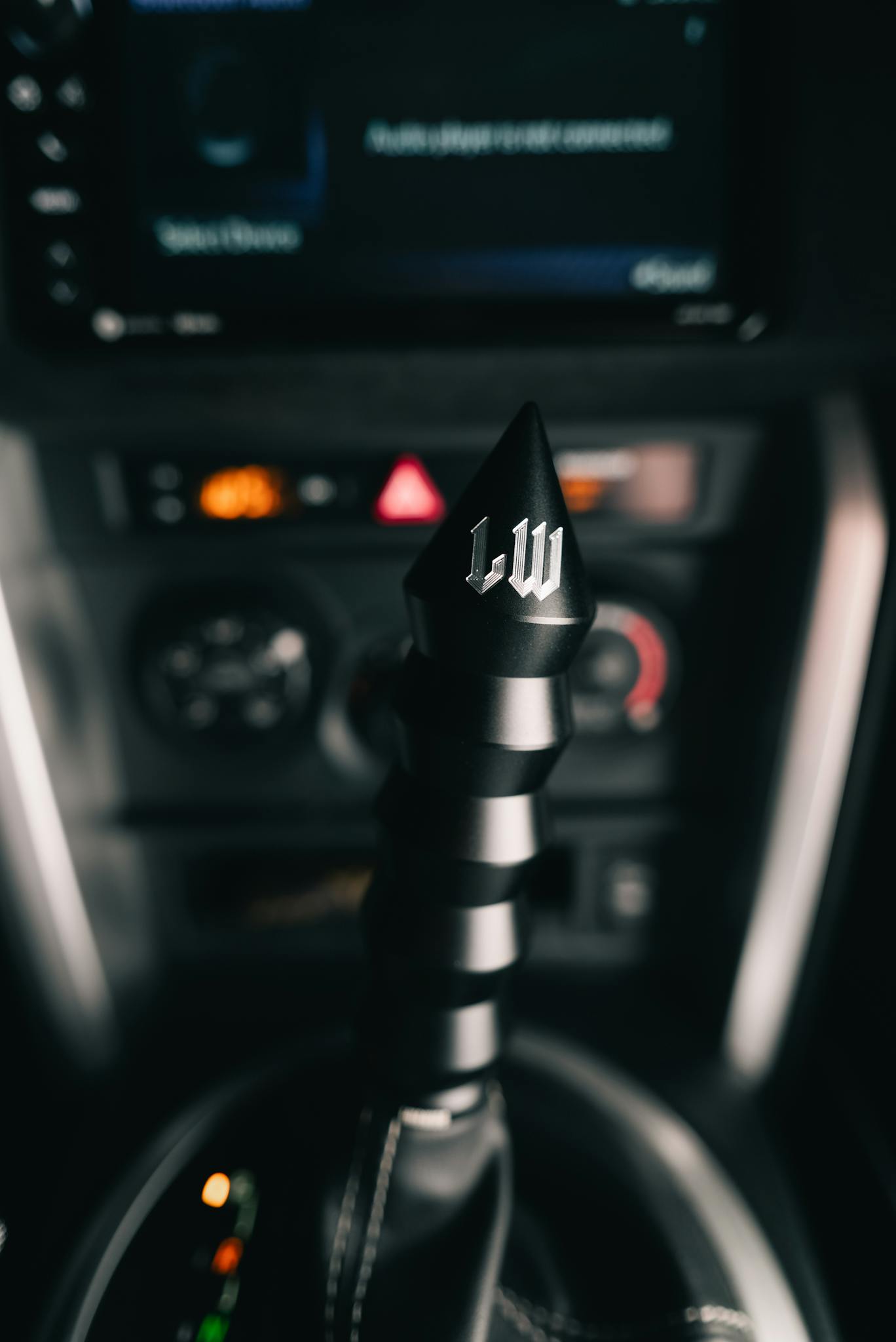 Close-up view of a stylish black metallic gear shift knob in a car interior, modern and sleek design.